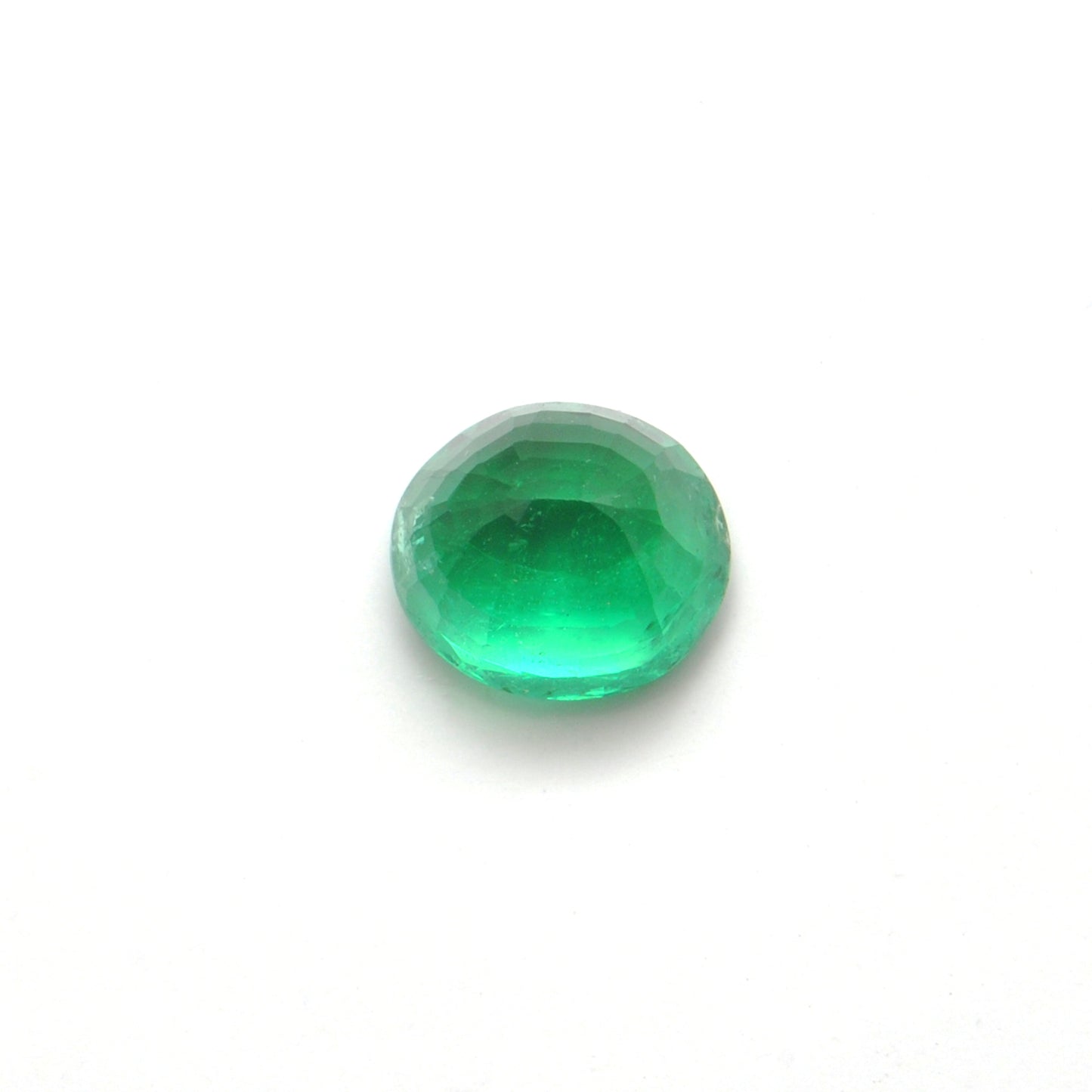 Close-up of a Kanika Creations natural Zambian emerald gemstone, 3.05 carats, oval faceted cut, 8.5x9.5mm, showcasing rich green color and stunning clarity.