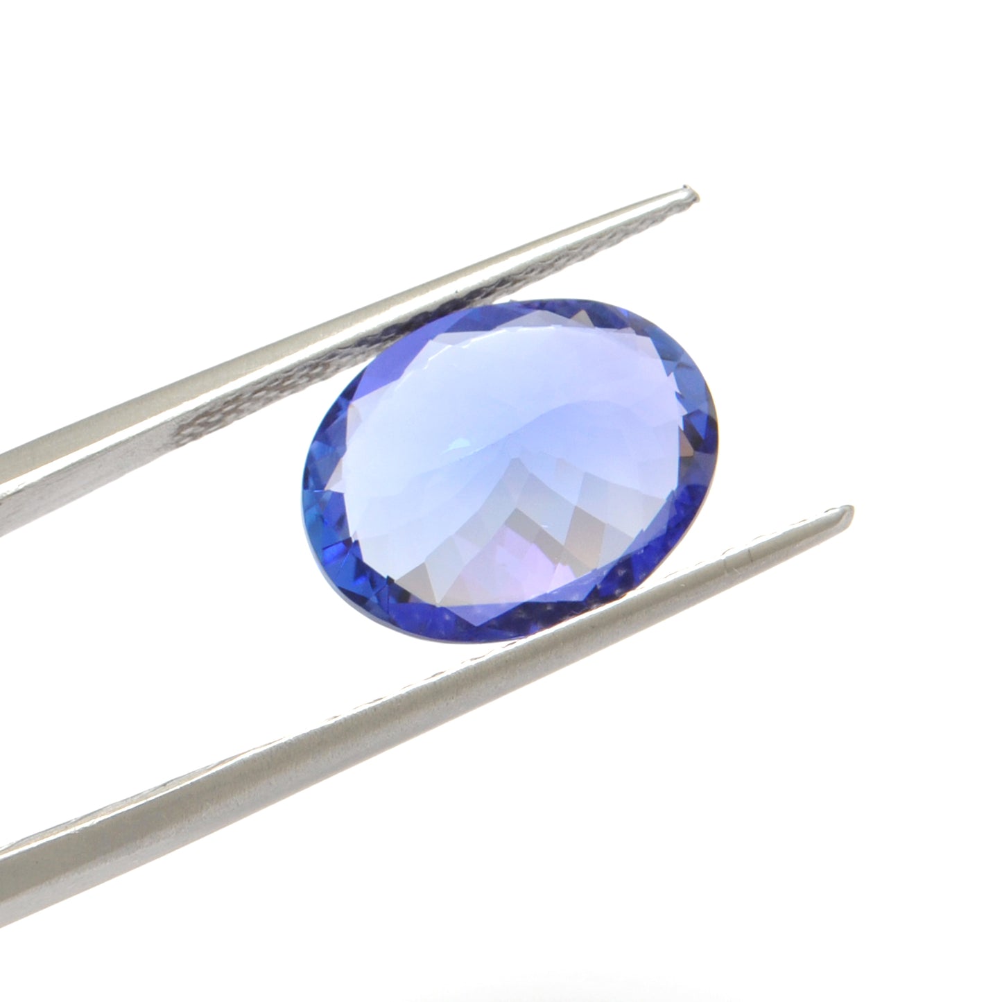 Close-up of a Kanika Creations natural tanzanite gemstone, 7.65 carats, faceted oval cut, 11.5x14.5mm, showcasing violet-blue color and brilliant clarity.