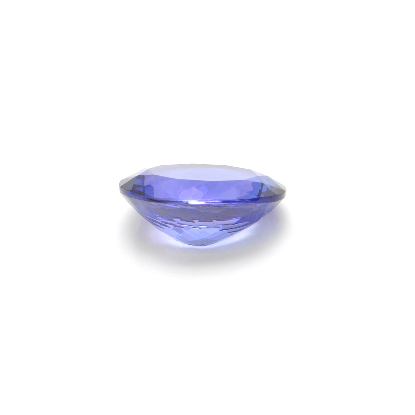 Close-up of a Kanika Creations natural tanzanite gemstone, 7.65 carats, faceted oval cut, 11.5x14.5mm, showcasing violet-blue color and brilliant clarity.