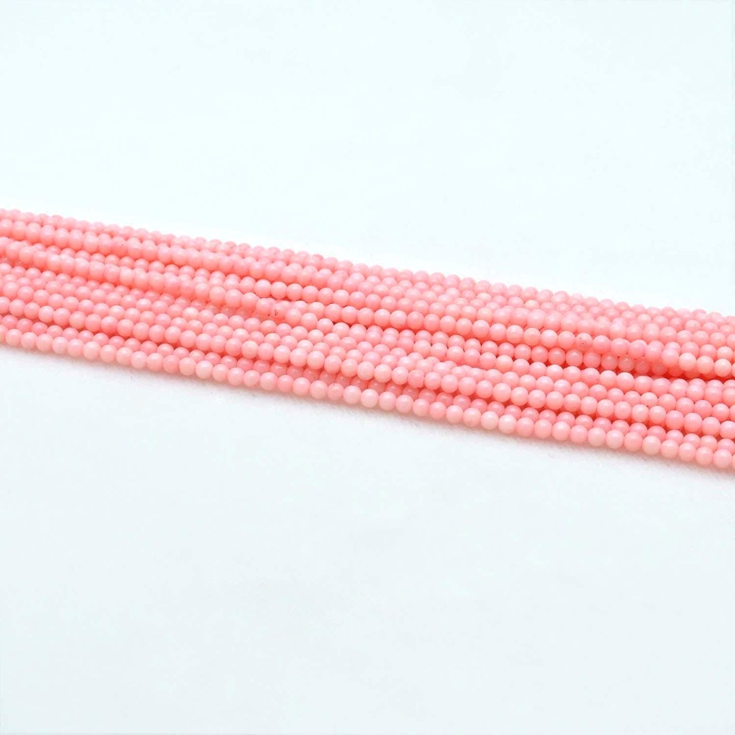 Pink coral plain round beads 12.5 inch strand overhead flat lay